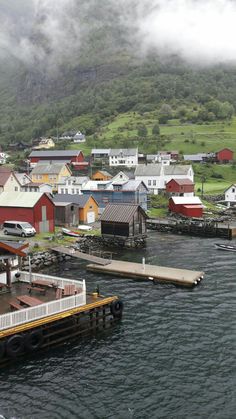 an aerial view of a small town on the water's edge with mountains in the background