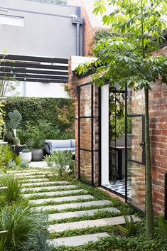 an outdoor garden with stone steps leading to the back door and patio area, surrounded by greenery