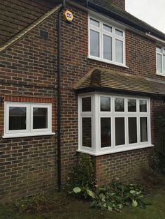 a brick house with white windows and plants in the front lawn area next to it