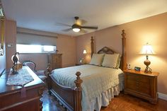 a bed sitting in a bedroom next to a dresser and lamp on top of a hard wood floor