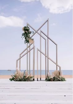 an outdoor ceremony setup with flowers and greenery in the shape of a house on the beach