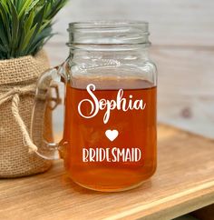 a mason jar filled with liquid sitting on top of a wooden table next to a potted plant