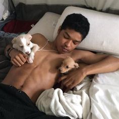 a man laying in bed with two puppies