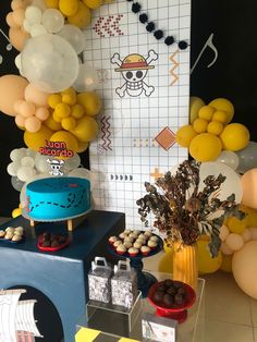 a table topped with lots of balloons and cake next to a wall covered in pirate decorations