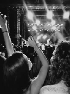 a crowd of people at a concert with their hands in the air