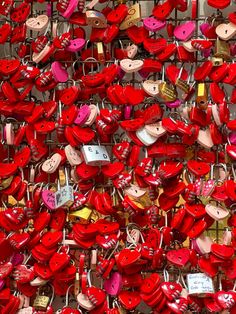 many red hearts are attached to the wall with padlocks and locks on them