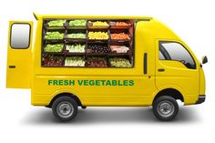 a yellow food truck with fresh vegetables on the front and side shelves in green lettering