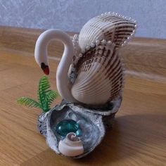 a white swan figurine sitting on top of a wooden table next to an open shell