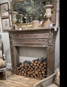 a fireplace with logs stacked on top of it in front of a mirror and chair