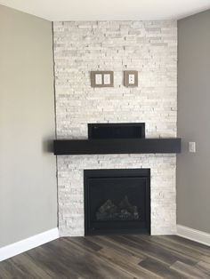 an empty living room with a white brick fireplace