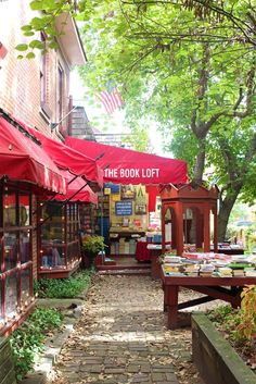 an outdoor book store with red awnings and stone walkway leading up to it