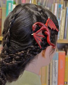 a woman with red dragon hair clips on her head in front of bookshelves