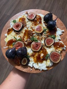 a person holding a pizza with figs and cheese on it