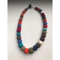 a multicolored necklace is hanging on a white wall