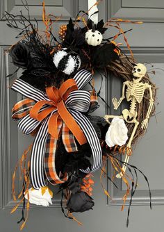 a halloween wreath with skeletons and pumpkins on the front door, decorated with black and orange ribbons