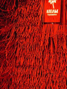 a red wall covered in sticks with a sign that says atme on it's side