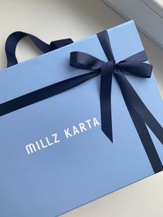 a blue box with a black ribbon on it that says millz karta