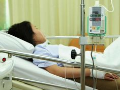 a woman laying in a hospital bed next to an iv machine with thermometer on it