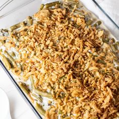 a casserole dish filled with green beans, rice and other toppings on a white table