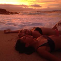 two women laying on the beach at sunset