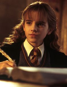 a young boy with long hair wearing a tie and writing on a piece of paper