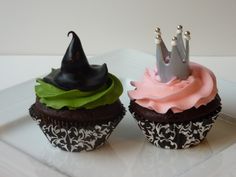 two cupcakes with pink frosting and black icing, one has a crown on top