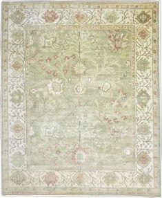 an antique rug with floral design on the center and border in green, beige and pink colors