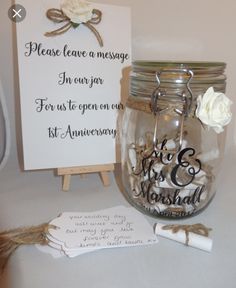 there is a mason jar with wedding decorations in it and a sign that says please leave a message i'm over for us to open each first anniversary