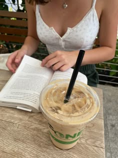 a woman sitting at a table with an open book and coffee in front of her