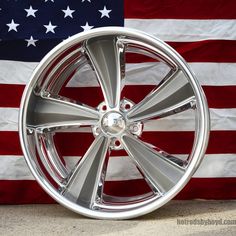 an american flag is in the background behind a wheel on a car's rim