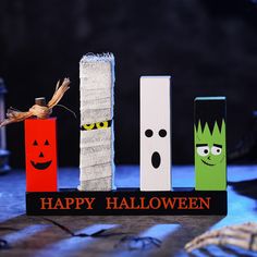 halloween decorations made out of wooden blocks with faces and eyes on them, sitting in front of a black background