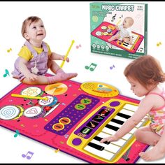 two young children playing with music instruments on a play mat and an electronic keyboard in front of them