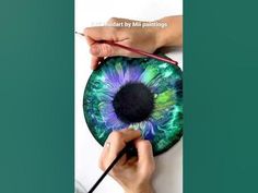 someone is painting an eyeball with green and blue colors