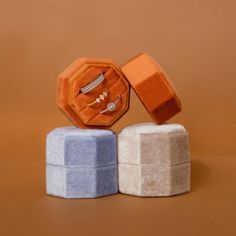 an orange ring sits on top of two blue and white blocks with jewelry in them