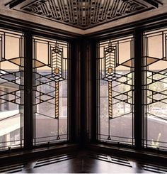 two large stained glass windows sitting inside of a wooden floored room next to a window