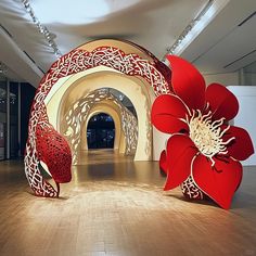 two large red flowers sitting on top of a hard wood floor next to a tunnel