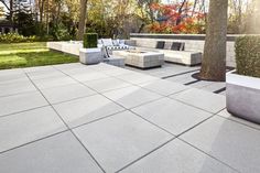 an outdoor patio with concrete furniture and trees in the background