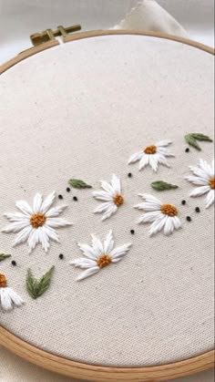 a close up of a embroidery on a piece of cloth with white and orange flowers