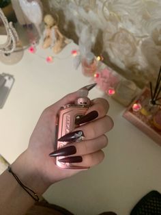 a woman's hand holding a pink and black manicured nail polish bottle