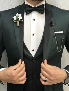 a man in a tuxedo and bow tie is holding his hands on his chest