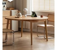 a wooden table with two chairs and a lamp on it in front of a window