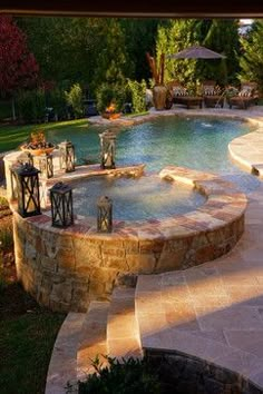 an outdoor hot tub surrounded by stone steps and patio furniture next to a swimming pool