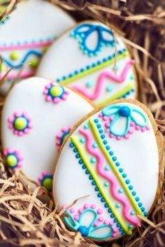 three decorated cookies sitting in some hay