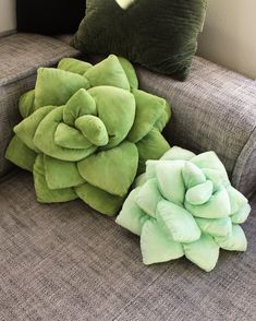 two green pillows sitting on top of a couch next to a pillow with a flower