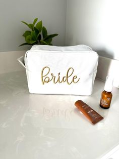 the bride cosmetic bag is sitting next to an orange bottle on a white countertop