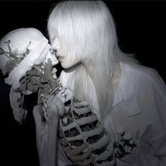 a woman with white hair holding a skeleton