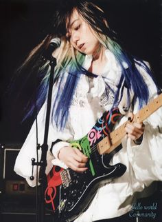 a woman with blue hair playing an electric guitar