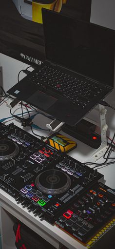 a laptop computer sitting on top of a desk next to a dj's controller