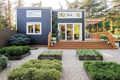 a blue house with lots of plants and trees in the front yard, along with steps leading up to it