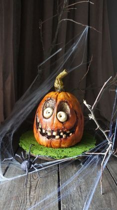 a carved pumpkin with eyes and mouth sitting on top of a wooden table in front of a net